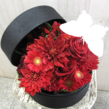 黒の丸い箱に情熱的な赤バラのアレンジメント